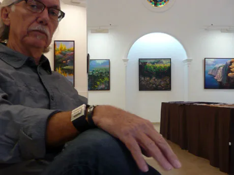 Antoni Mas Rexach, assegut entre els seus quadres durant una exposició.